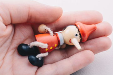 Wooden pinocchio doll with his long nose - obrazy, fototapety, plakaty