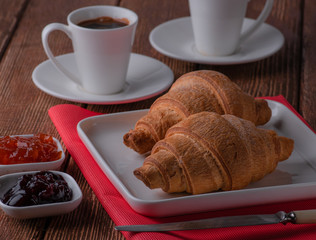 croissant with coffee and jam made of cherry and apricot. Put on a stand tree