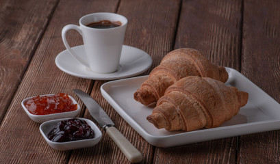 croissant with coffee and jam made of cherry and apricot. Put on a stand tree