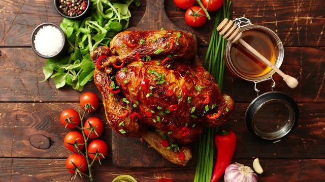 Roasted whole chicken or turkey served on wooden chopping board with chilli pepers and chive. With ingredients on sides. Shot from above with copy space for text.