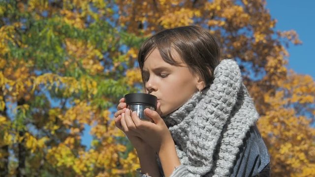 The child drinks tea in the fresh air.