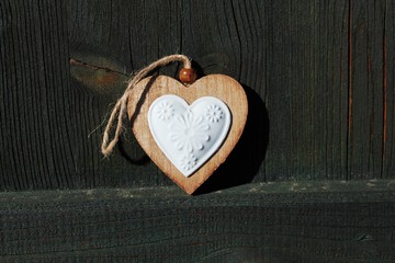 Rustikales Herz aus Holz mit Keramik vor dunkelgrüner Holzwand, Weihnachtsdekoration