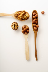 Walnuts and hazelnuts in wooden spoons isolated on white background. Top view with copy space