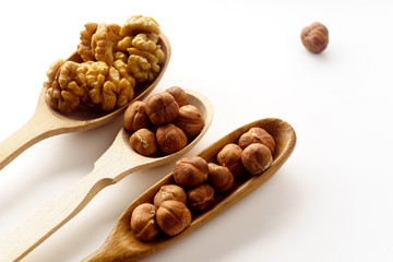 Walnuts and hazelnuts in wooden spoons isolated on white background. Top view with copy space