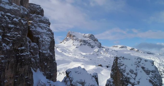 Forward aerial through majestic Cinque Torri rocky mounts showing ski tracks. Sunny day with cloudy sky.Winter Dolomites Italian Alps mountains outdoor nature establisher.4k drone flight