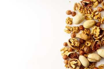 Overhead image of a group of various nuts with nutshells isolated on white background with copy space