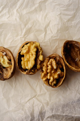 Raw walnuts in cracked nutshells on parchment paper. Overhead view