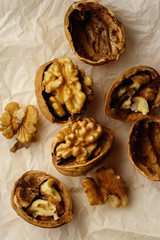 Raw walnuts in cracked nutshells on parchment paper. Overhead view