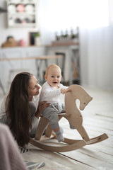 Mom with her son, baby swinging on toy horse