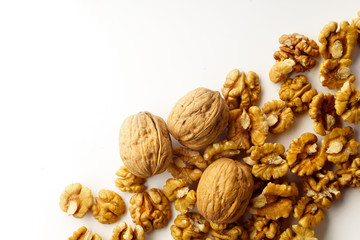 Top view of a heap of raw walnuts with a nutshell on white background isolated with copy space