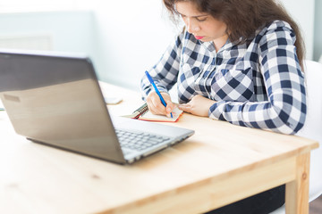 Business and people concept - Young woman writes notes in a notebook on a white table in office