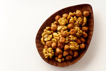 Overhead image of assorted nuts on wooden tray on white background with copy space