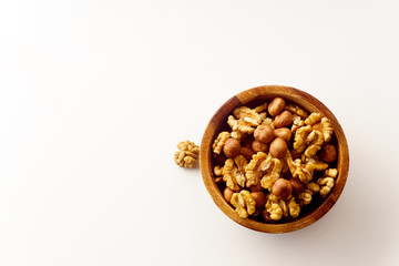 Overhead image of assorted nuts in wooden bowl on white background with copy space