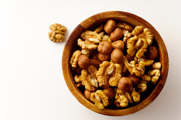 Overhead image of assorted nuts in wooden bowl on white background with copy space