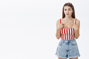 Waist-up shot of concerned displeased stylish and arrogant woman in pin-up headband and striped top...