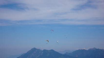 Fototapeta na wymiar paragliders flying in the sky above the mountains of Switzerland