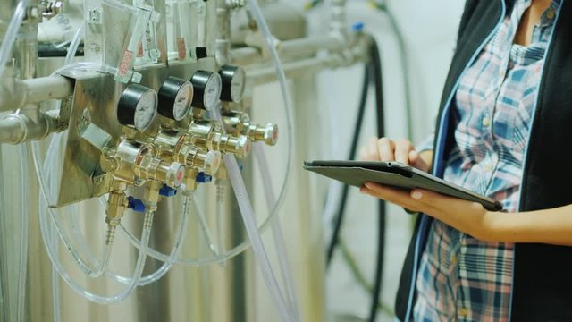 Quality control in production. Hands of an engineer with a tablet on the background of instruments and manometers