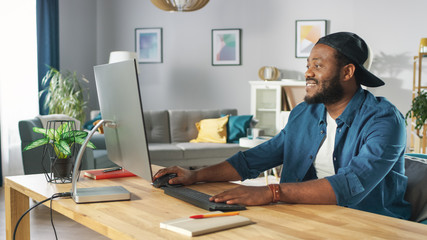 Portrait of the Handsome African American Programmer Working on a Personal Computer while Sitting at His Desk at Home.