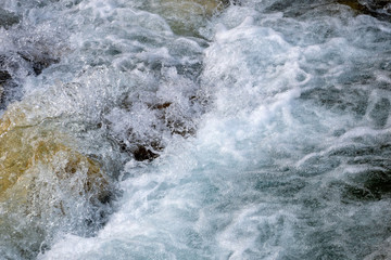 Powerful flow of water over the stones, mountain river close up.