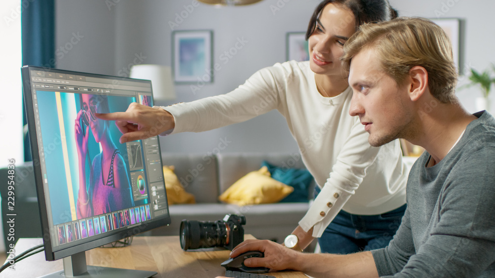 Poster male and female professional editors talk while working in photo editing app / software on a persona