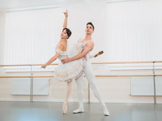 Rehearsal in the ballet hall or studio with minimalism interior. Young professional sensual couple in beautiful costumes dancing together © kohanova1991