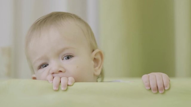 Lovely blue eyes baby portrait, child holding with little hands crib margin 