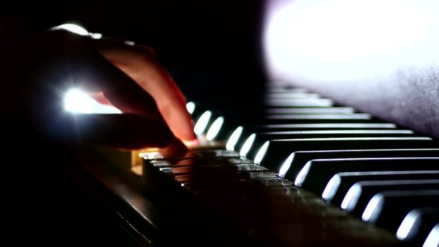 Playing the piano - fingers of a pianist in the rays of light