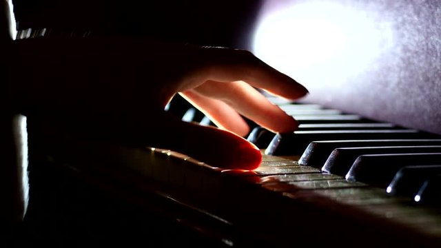 Playing the piano - fingers of a pianist in the rays of light