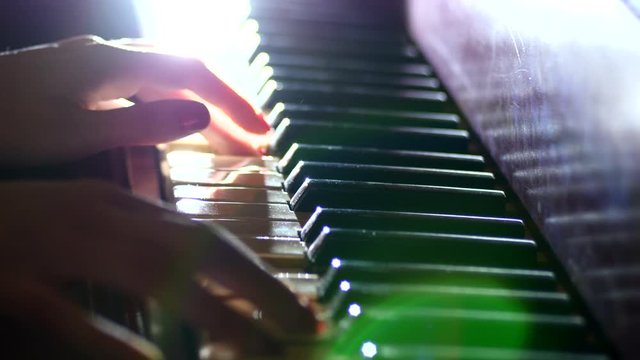 Playing the piano - fingers of a pianist in the rays of light