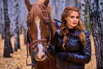 Portrait of a young beautiful woman with long brown hair. Woman on a horse walk in the forest.