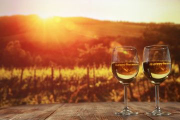 Two glasses with wine on a wooden table in an autumn setting   