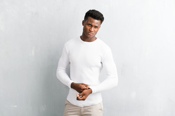 Young afro american man posing on textured grey wall