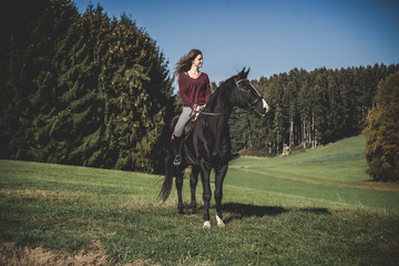 Junge schöne Frau und schwarzes Pferd Ausritt, reiten, Derssur, Reiterin