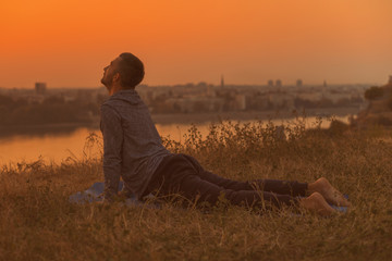 Man doing yoga on sunset with city view,Bhujangasana/Cobra Pose.
