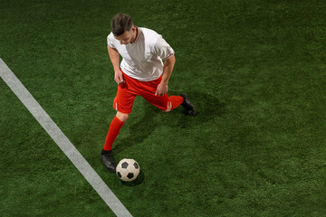 Football player tackling for ball over green grass background. Professional football soccer player in motion at studio. Fit jumping man in action, jump, movement at game.