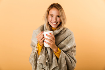 Happy woman in plaid isolated over yellow wall background holding cup of tea.