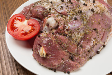 pickled turkey meat with spices on a white plate, surrounded by scattered peppers, on wooden boards, macro photography