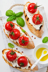 Sandwich with baked cherry tomatoes, garlic, olive oil and curd cheese on white background. Italian Cuisine. Top view.