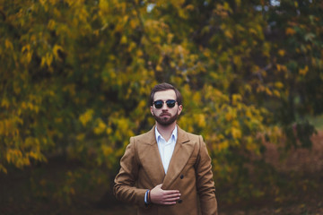 stylish man in elegant coat posing in park