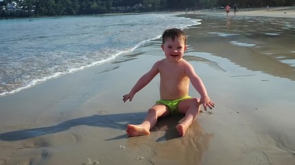 Cute Toddler Splashes and Throws Sand on the Beach in Thailand