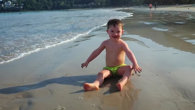 Cute Toddler Splashes and Throws Sand on the Beach in Thailand