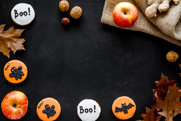 Halloween composition with autumn harvest as dried autumn leaves, pumpkin, apple and cute round hallooween badges with rats, ghousts, Boo text on black background top view copy space frame