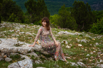 Young happy woman in long dress on the mountainside.