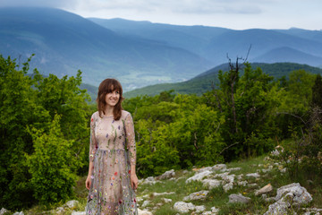 Naklejka premium Young happy woman in long dress on the mountainside.