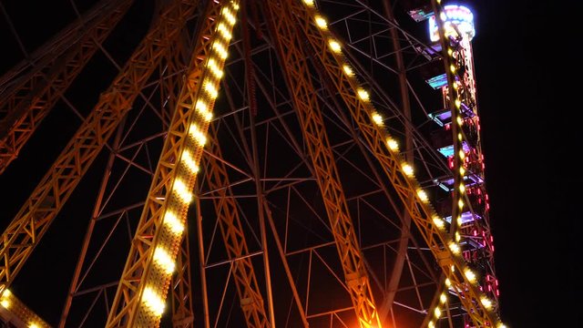 Colorful illumination bokeh effect light flashing on big ferris wheel roller coaster in amusement park fair at night sky