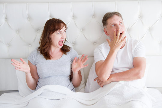 Middle age couple with quarrel problem in relationship in bed. Family life. Copy space. Boring and sleepy yawn concept.