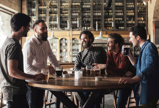 Group Of Men Laughing And Drinking Beer In Bar