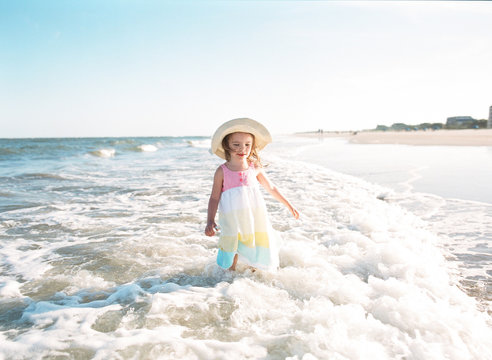 little girl standing in ocean on beach