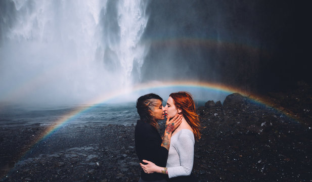Side view of couple kissing in front of waterfall