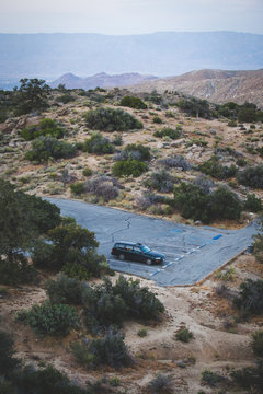 An older station wagon parked in a desert parking lot at dusk